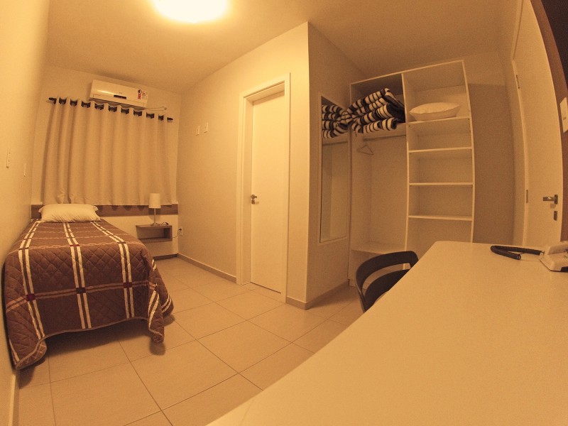 Apartamento Single do Gaúcho Hotel, com uma cama e armário.